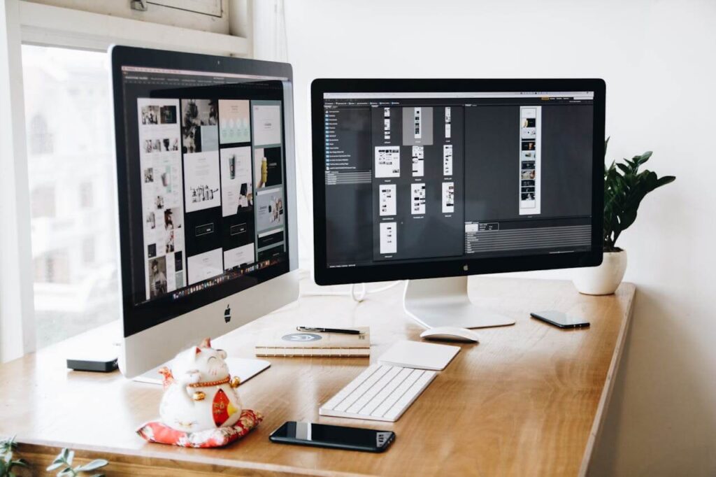 Dual-monitor setup displaying website design mockups