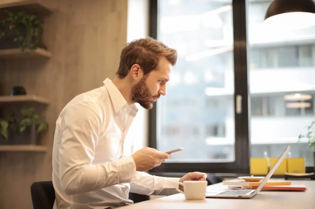Businessman multitasking with coffee and computer representing custom web design