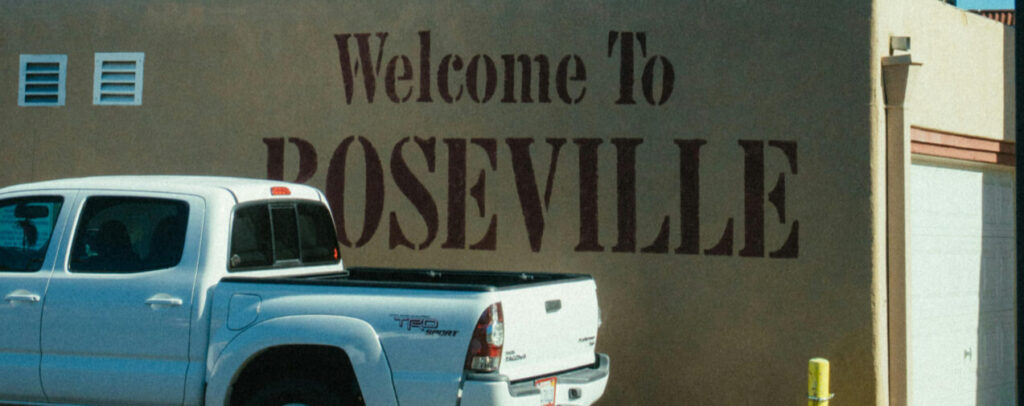 City welcome sign in Roseville, partially obscured by a white pickup